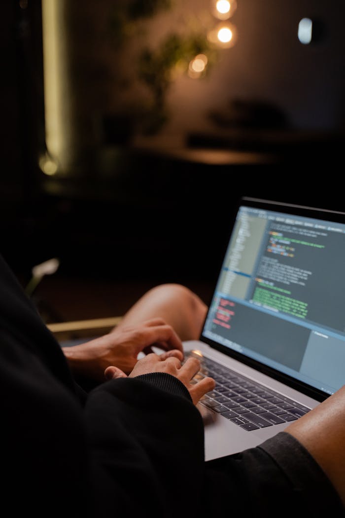 Mastering the First Impression: Your intriguing post title goes here Focused hands typing code on a laptop in a dimly lit room, showcasing programming activities.